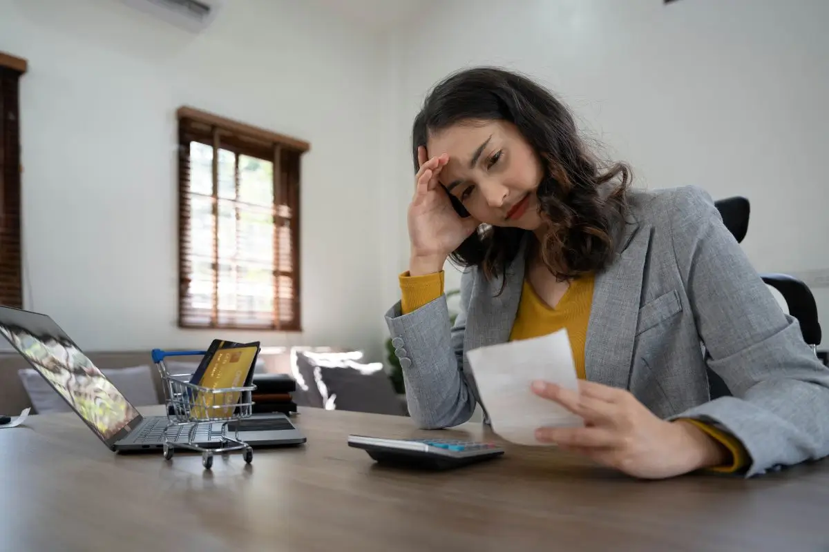 Concerned woman reviewing bills and calculating finances at home with a laptop and credit cards, representing unexpected wage garnishment without employer notice.