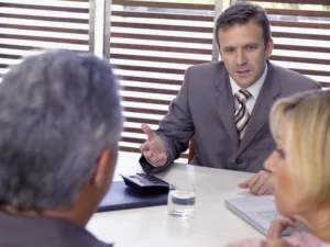 Business meeting with man in suit speaking and others listening, representing a 341 meeting of creditors in Tampa where a bankruptcy debtor answers questions from the trustee and creditors
