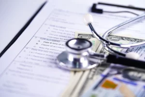 Medical stethoscope and cash on a patient’s medical record, illustrating overwhelming medical bills and bankruptcy options available to individuals in Florida facing healthcare debt.