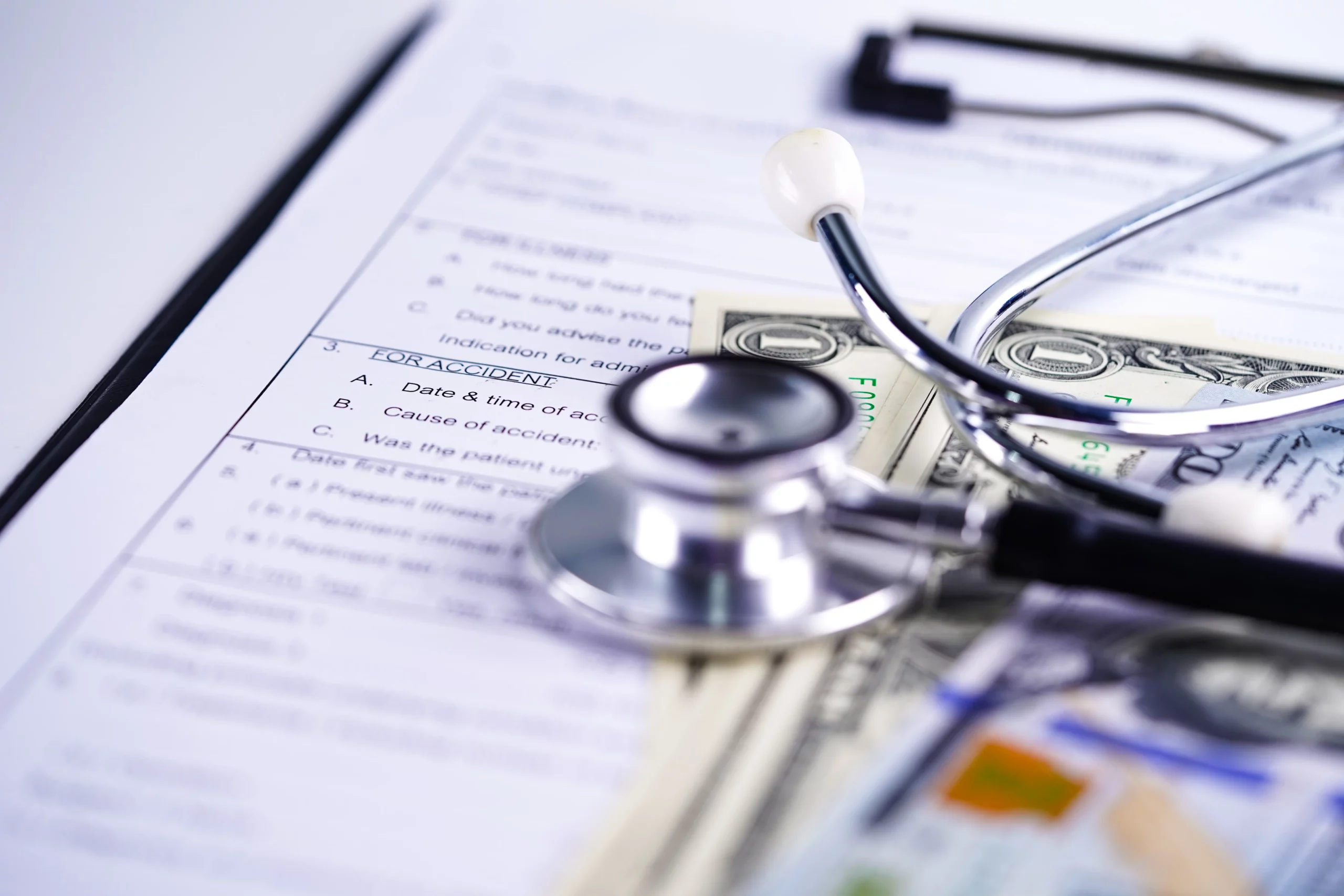 Medical stethoscope and cash on a patient’s medical record, illustrating overwhelming medical bills and bankruptcy options available to individuals in Florida facing healthcare debt.